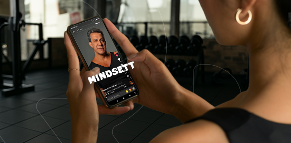 Pessoa segurando celular com conteúdo MindSETT em uma academia