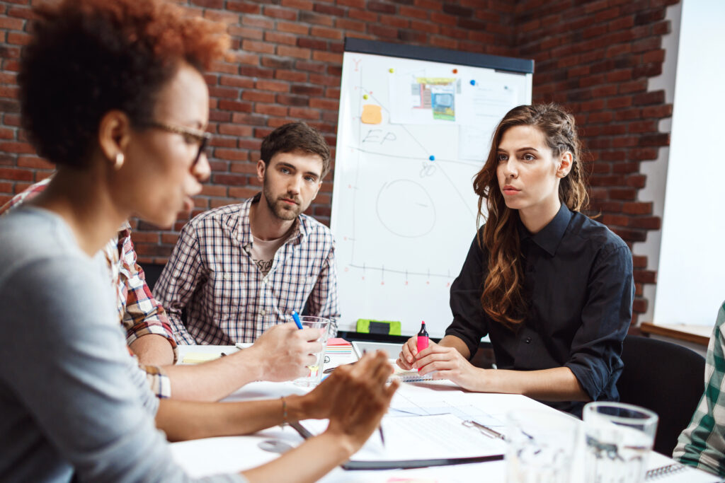 Três pessoas sentadas em uma reunião em uma agência de marketing