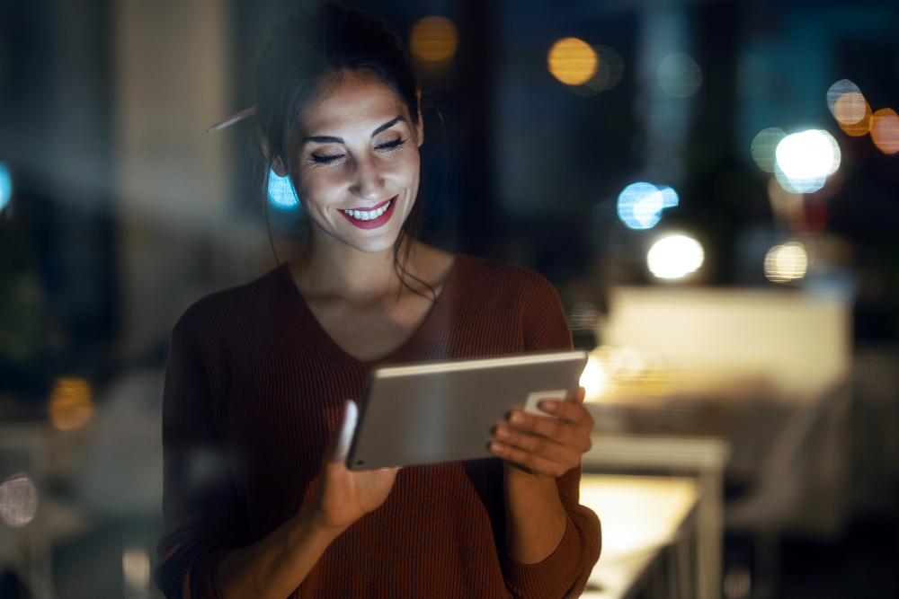 Mulher sorrindo olhando para a tela de um tablet